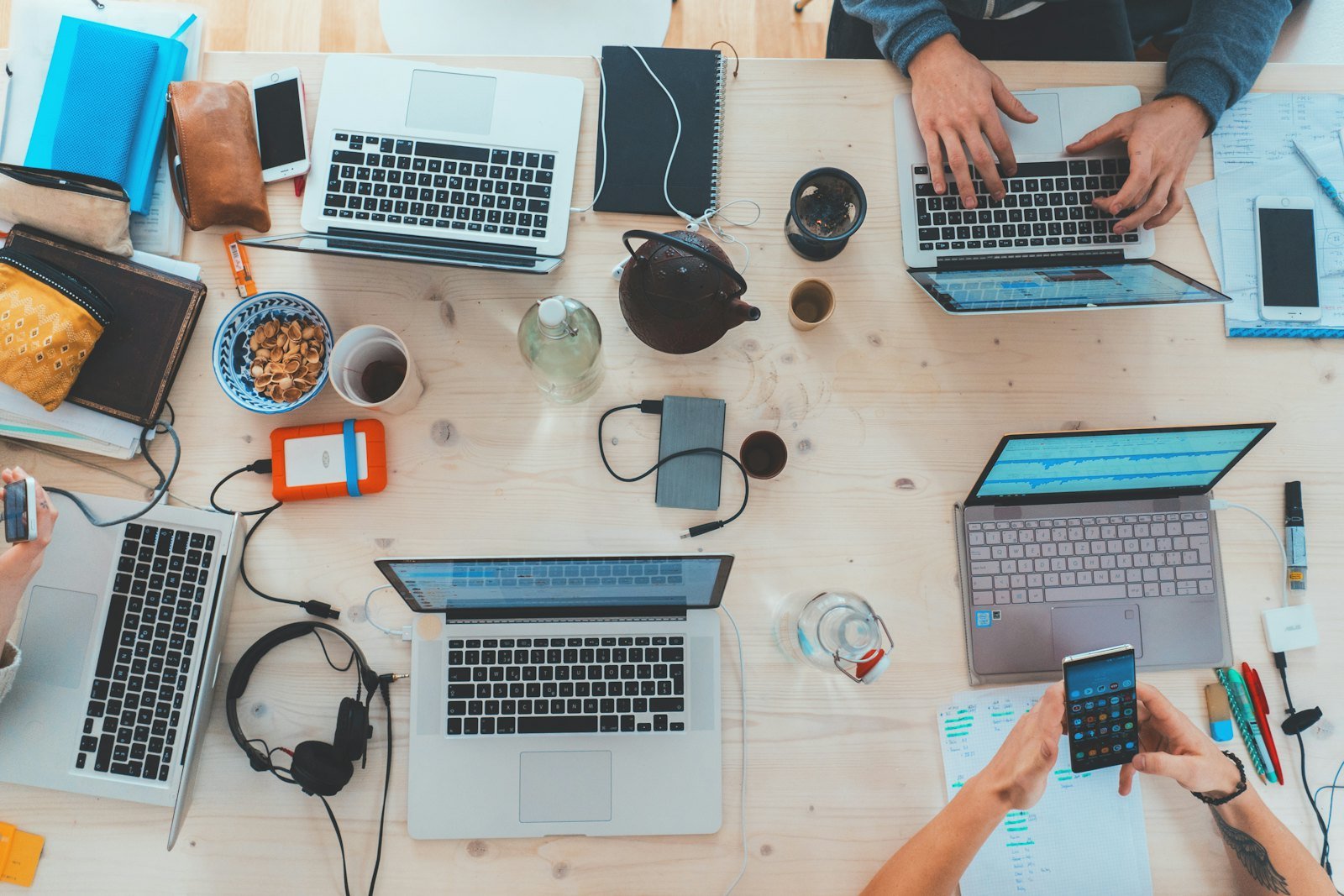 A team at a shared desk: laptops, phones and notes