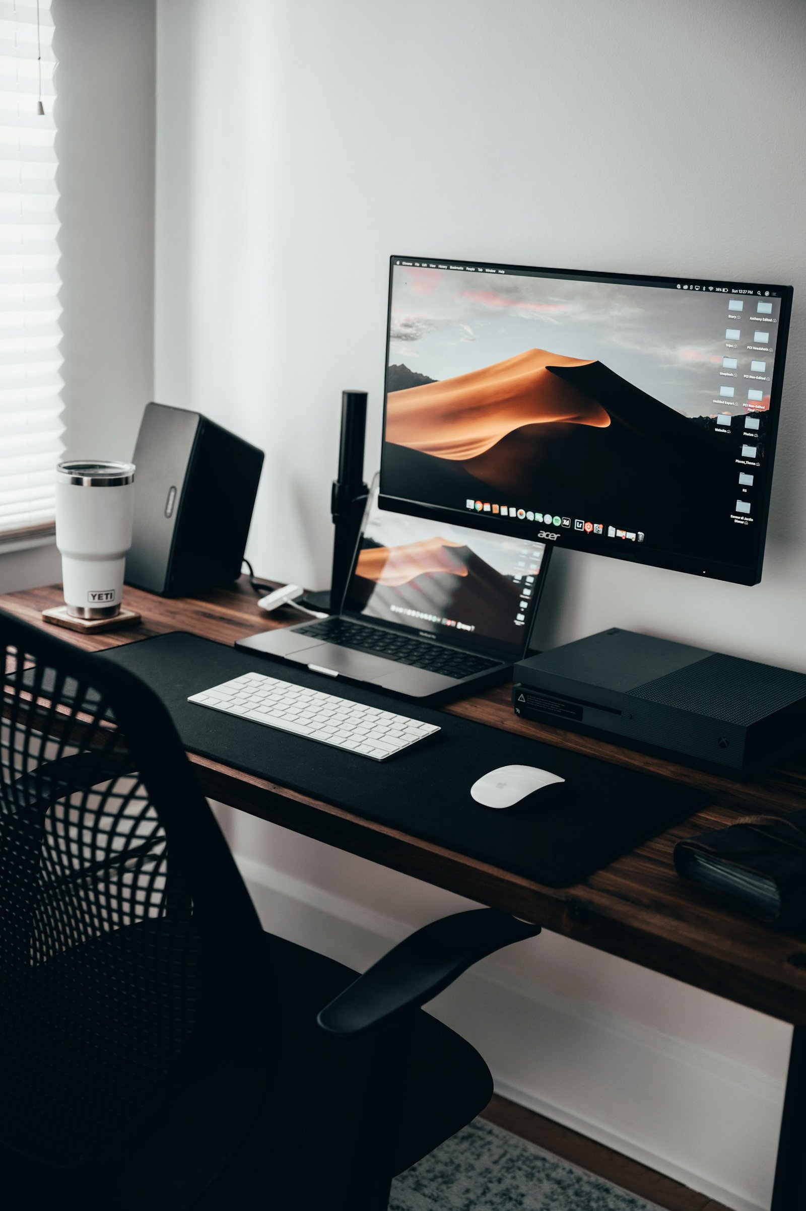 A laptop, notepad and coffee on a wooden desk