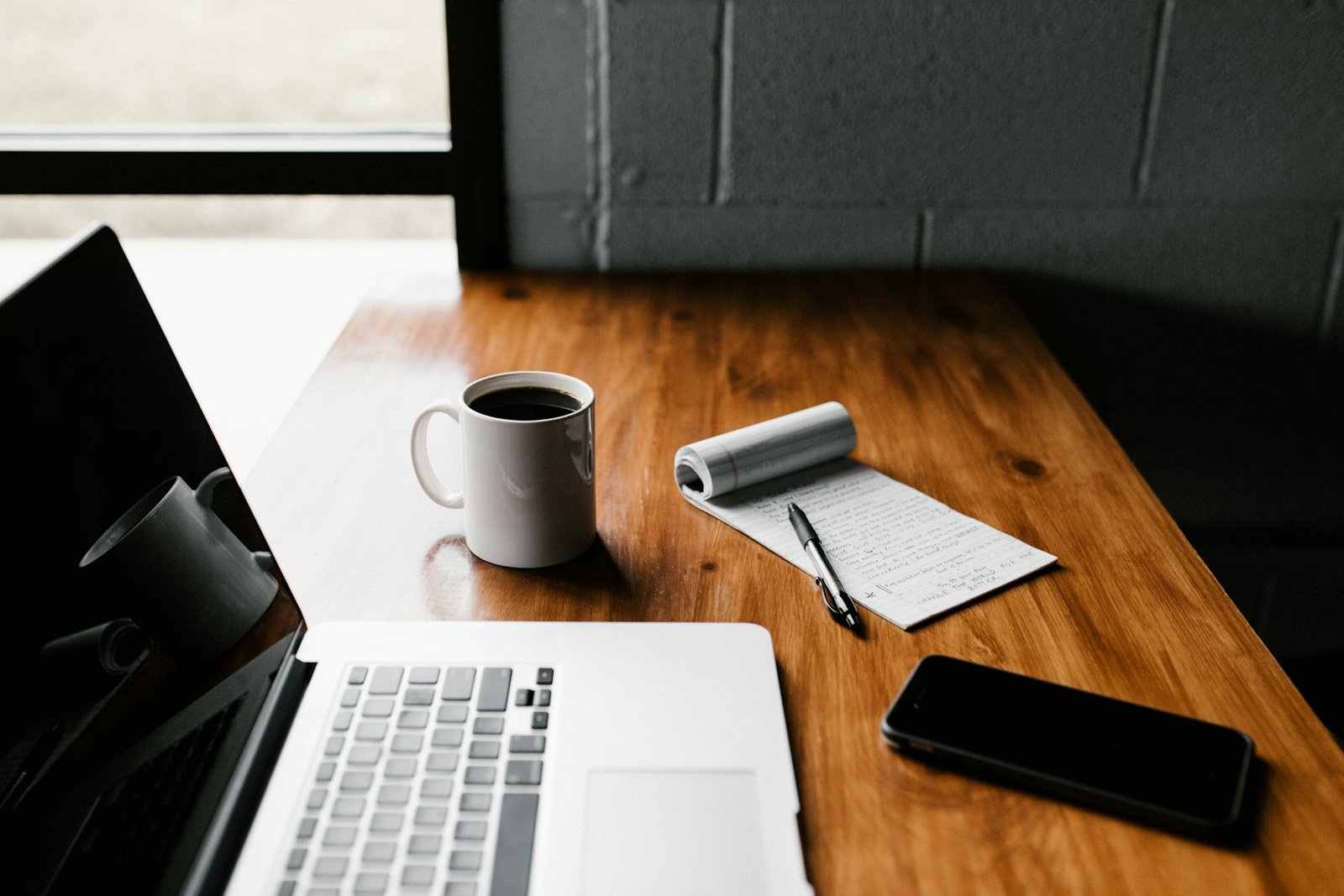 A work desk: laptop, notepad and coffee